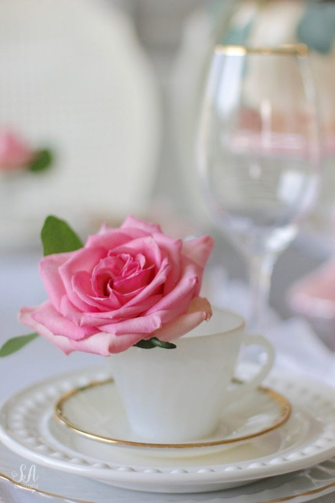 milk glass teacup, fresh pink roses, crystal chandelier, crystorama chandelier, white faux pumpkin floral arrangement, romantic floral brunch tablescape, girls table, brunch table, girlfriends party, fall party, fall tablescape, blush pink ruffle dinner linen napkins, white ruffle table runners, gold flatware, white beaded pottery barn dishes, white beaded world market dishes, gold rimmed goblets wine glasses, pink tablescape, pink table decor, place settings, vintage milk glass dinnerware