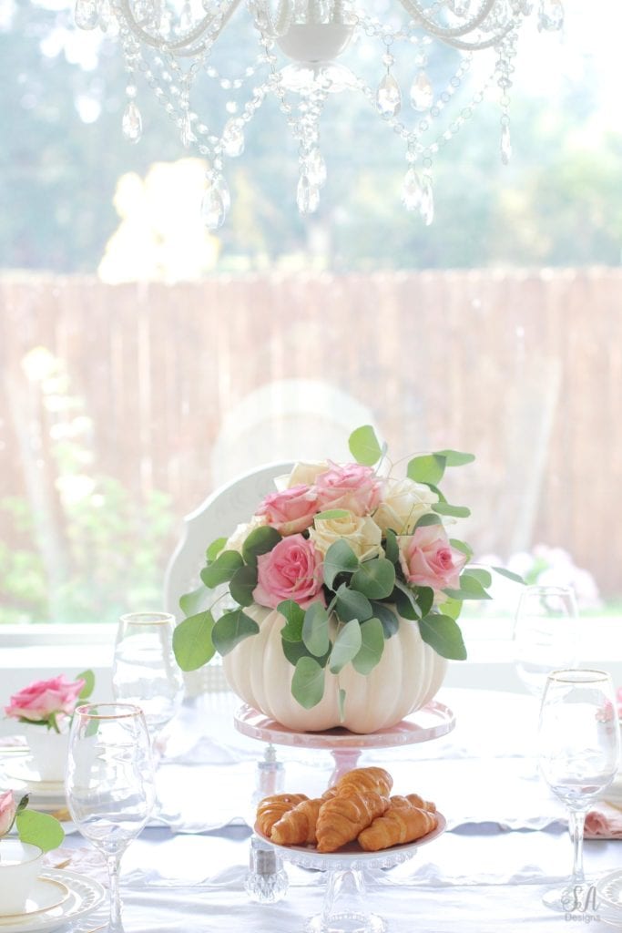 milk glass teacup, fresh pink roses, crystal chandelier, crystorama chandelier, white faux pumpkin floral arrangement, romantic floral brunch tablescape, girls table, brunch table, girlfriends party, fall party, fall tablescape, blush pink ruffle dinner linen napkins, white ruffle table runners, gold flatware, white beaded pottery barn dishes, white beaded world market dishes, gold rimmed goblets wine glasses, pink tablescape, pink table decor, place settings, vintage milk glass dinnerware