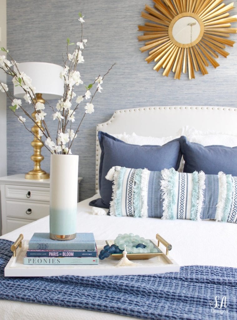 blue and white decor, guest bedroom design, gold brass accents, sunburst mirror, blue faux grasscloth wallpaper, white headboard, decorating with books, gold lamps