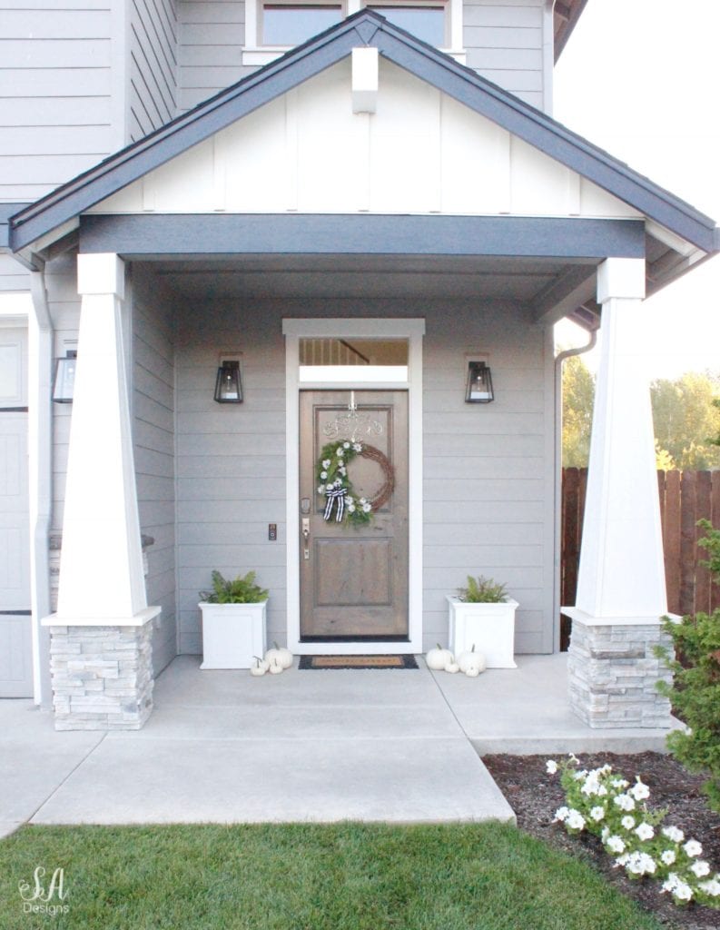 loveliest looks of fall tour 2018, summer adams, craftsman style home fall front porch mini white pumpkins, fall diy wreath, white planters, asymmetrical fall wreath striped black ribbon, ferns, modern farmhouse outdoor lighting fixtures