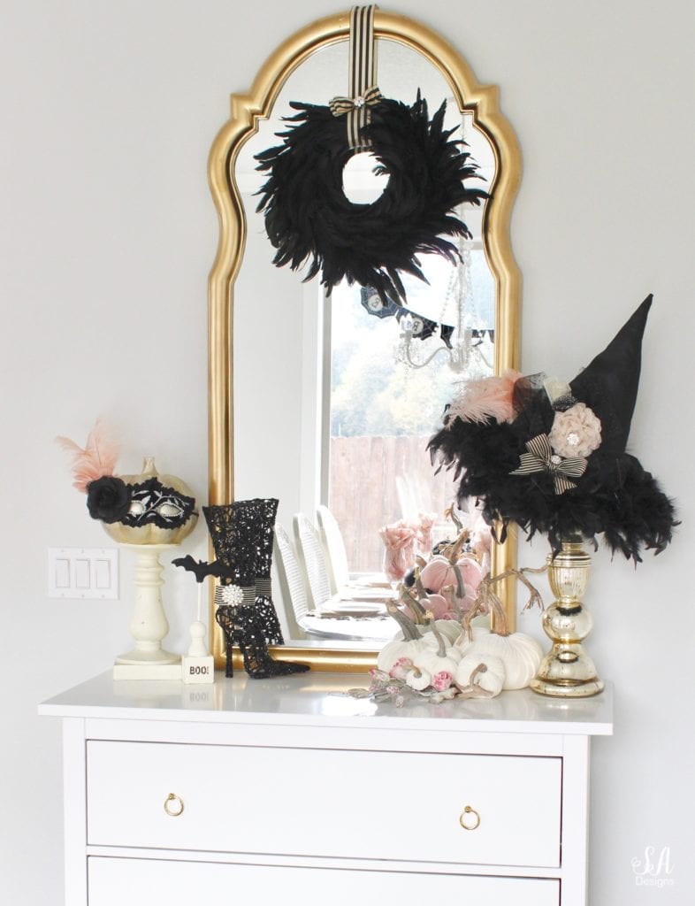 halloween living room, glam chic classy elegant halloween decor, glam halloween mantel, pink and black halloween decor, white interiors, black white gold leopard print embroidered pillow covers CB2, blush mohair faux fur throw pillows, white tufted chesterfield sofas, pier1 blush vases, glam candles, halloween mantel decor, bling skull, gold tray, brass crystal chandelier, tv over mantel, tv above mantel mantle, halloween buffet