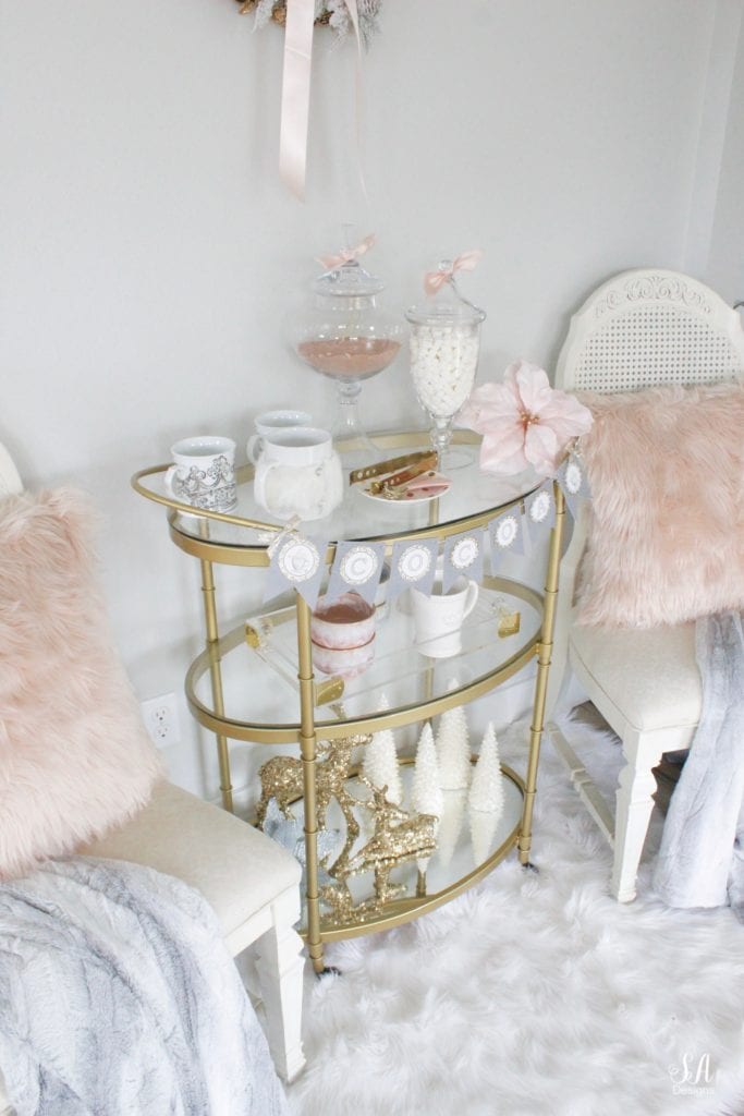 faux fur white rug, faux fur dusty blue throw blankets, blush peach pink faux fur throw pillows, vintage dining chairs white, brass gold bar cart 3 tier, diy hot cocoa station bar cart banner garland, glitter sequin white faux deer head, deer wall decoration, flocked white wreath, gold opalhouse brass wreath, blush and blue christmas, apothecary jars for hot chocolate, gold sequin glitter deer, white glitter christmas tree candles, pier one faux fur mug, acrylic brass tray, anthropologie home blue and pink bowls, white crown mugs, deer head with rhinestone crown, deer with blush satin bow