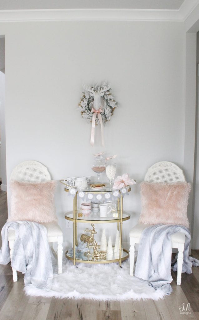 faux fur white rug, faux fur dusty blue throw blankets, blush peach pink faux fur throw pillows, vintage dining chairs white, brass gold bar cart 3 tier, diy hot cocoa station bar cart banner garland, glitter sequin white faux deer head, deer wall decoration, flocked white wreath, gold opalhouse brass wreath, blush and blue christmas, apothecary jars for hot chocolate, gold sequin glitter deer, white glitter christmas tree candles, pier one faux fur mug, acrylic brass tray, anthropologie home blue and pink bowls, white crown mugs, deer head with rhinestone crown, deer with blush satin bow