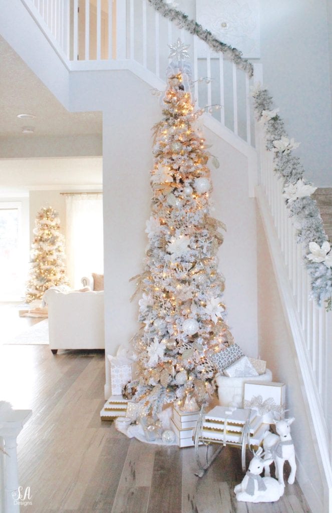 12 foot slim flocked christmas tree king of christmas, mixed metals christmas decor ornaments, whitel gold silver champagne christmas decor, glam christmas decor, elegant christmas decor, christmas sleigh, gift wrapping, presents underneath tree, white faux deer christmas figurines pier1, flocked garland