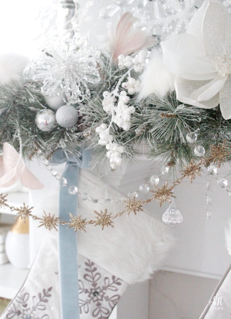 dreamy whimsical fantasy playful christmas mantel, faux fur stockings with snowflakes, christmas flocked garland with jewel rhinestone gold glitter pearl jewels garland, blush feather, faux fur pom poms, white glitter berry christmas stems, sparkly glitter christmas magnolia stems, dusty blue velvet ribbon, glitter snowflakes, joann fabric white swan figures, mercury glass candlesticks, cozy glam winter wonderland christmas, white fireplace marble tile