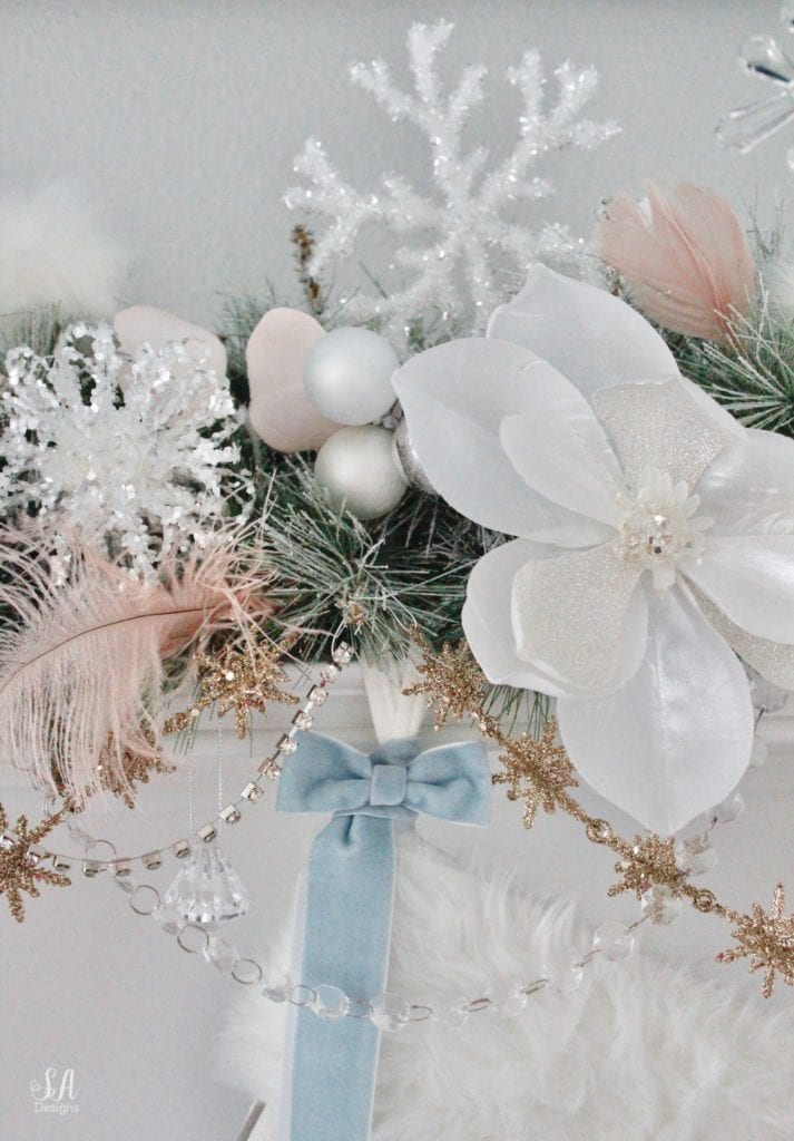 dreamy whimsical fantasy playful christmas mantel, faux fur stockings with snowflakes, christmas flocked garland with jewel rhinestone gold glitter pearl jewels garland, blush feather, faux fur pom poms, white glitter berry christmas stems, sparkly glitter christmas magnolia stems, dusty blue velvet ribbon, glitter snowflakes, joann fabric white swan figures, mercury glass candlesticks, cozy glam winter wonderland christmas, white fireplace marble tile