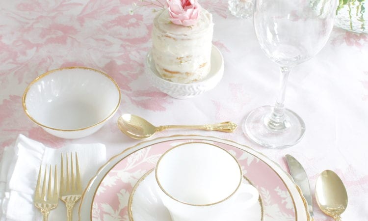 monique lhuillier pottery barn, pink floral tablecloth, pink floral plates, white kitchen design, vintage valentines day tablescape, valentines decor table, antique vintage milk glass plates teacups saucers gold rimmed, gold rimmed crystal goblets, vintage gold flatware, white ruffled napkins, individual mini naked cakes with fresh pink rose baby's breath