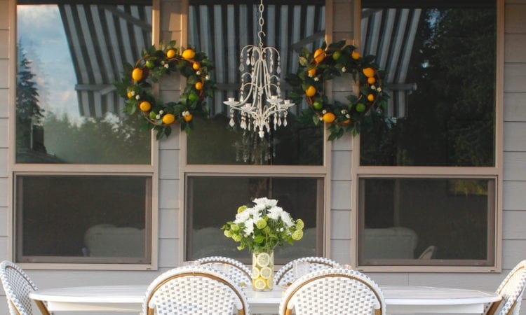 grey and white striped retractable awning, french outdoor patio, french style outdoor patio dining, french coastal backyard landscape dining outdoor design, english garden lemon tablescape, serena and lily outdoor umbrella, serena and lily grey white french bistro chairs, white oval outdoor dining patio table, outdoor patio table dining set, gold brass bar cart, lemon and fruit floral arrangement, outdoor patio chandelier, lemon tree