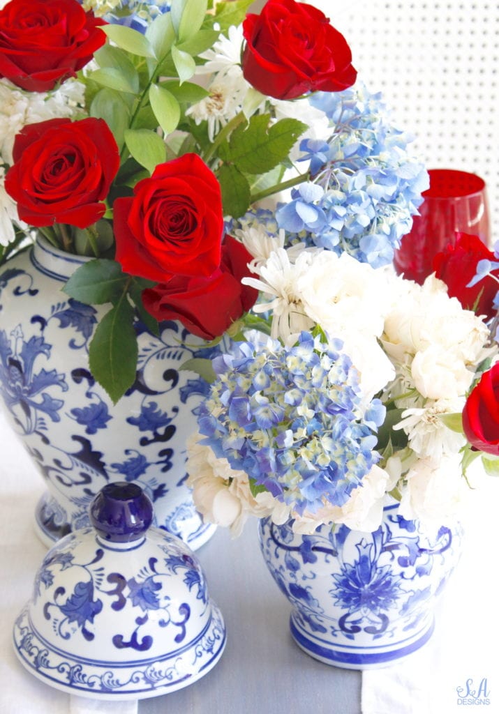 patriotic Tablescape, fourth of July table, red white and blue Tablescape table setting place setting, chinoiserie place setting, chinoiserie patriotic table, Aerin table place setting, Aerin plates Williams-Sonoma, scalloped plates, blue white plates, white ruffle dinner napkins, elegant gold flatware, red goblets, white ruffle table runners, white kitchen