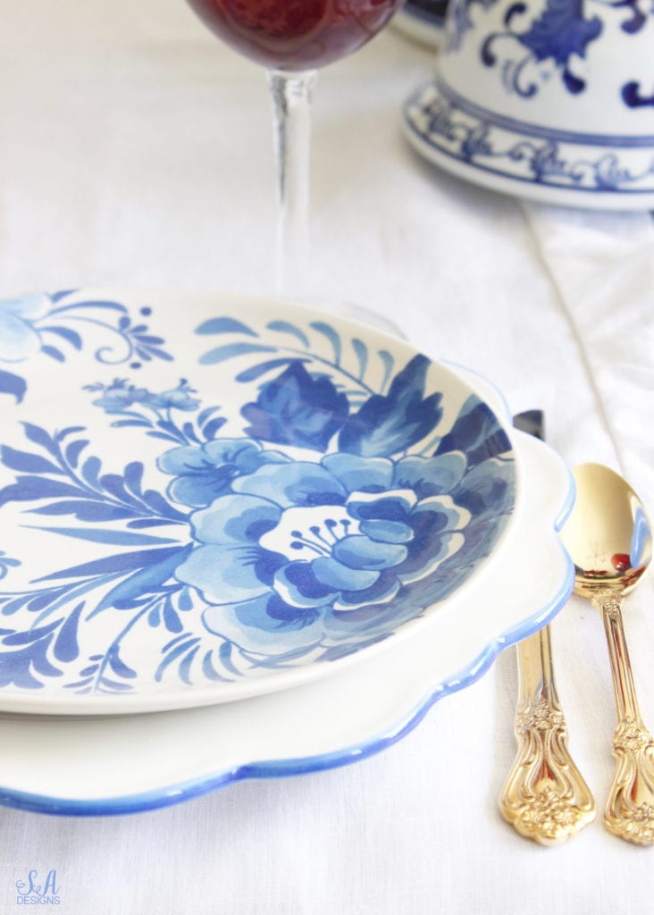 patriotic Tablescape, fourth of July table, red white and blue Tablescape table setting place setting, chinoiserie place setting, chinoiserie patriotic table, Aerin table place setting, Aerin plates Williams-Sonoma, scalloped plates, blue white plates, white ruffle dinner napkins, elegant gold flatware, red goblets, white ruffle table runners, white kitchen