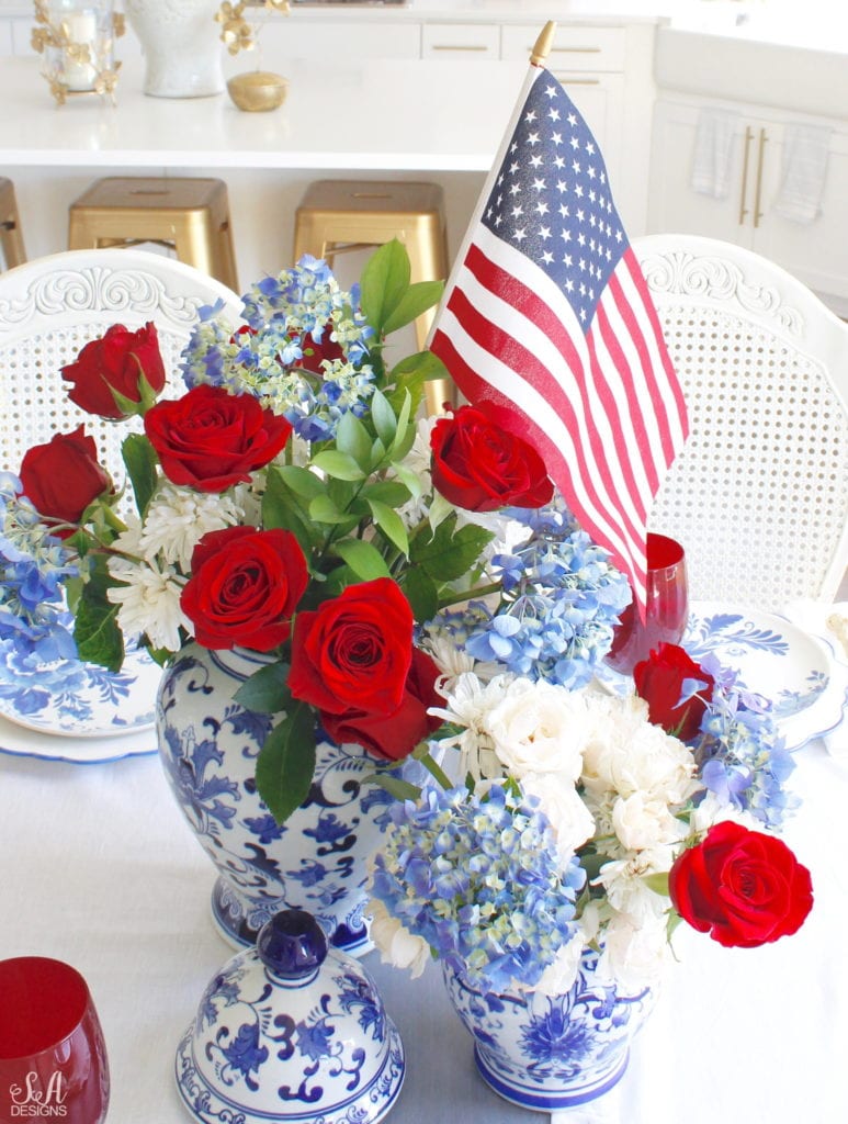 patriotic Tablescape, fourth of July table, red white and blue Tablescape table setting place setting, chinoiserie place setting, chinoiserie patriotic table, Aerin table place setting, Aerin plates Williams-Sonoma, scalloped plates, blue white plates, white ruffle dinner napkins, elegant gold flatware, red goblets, white ruffle table runners, white kitchen