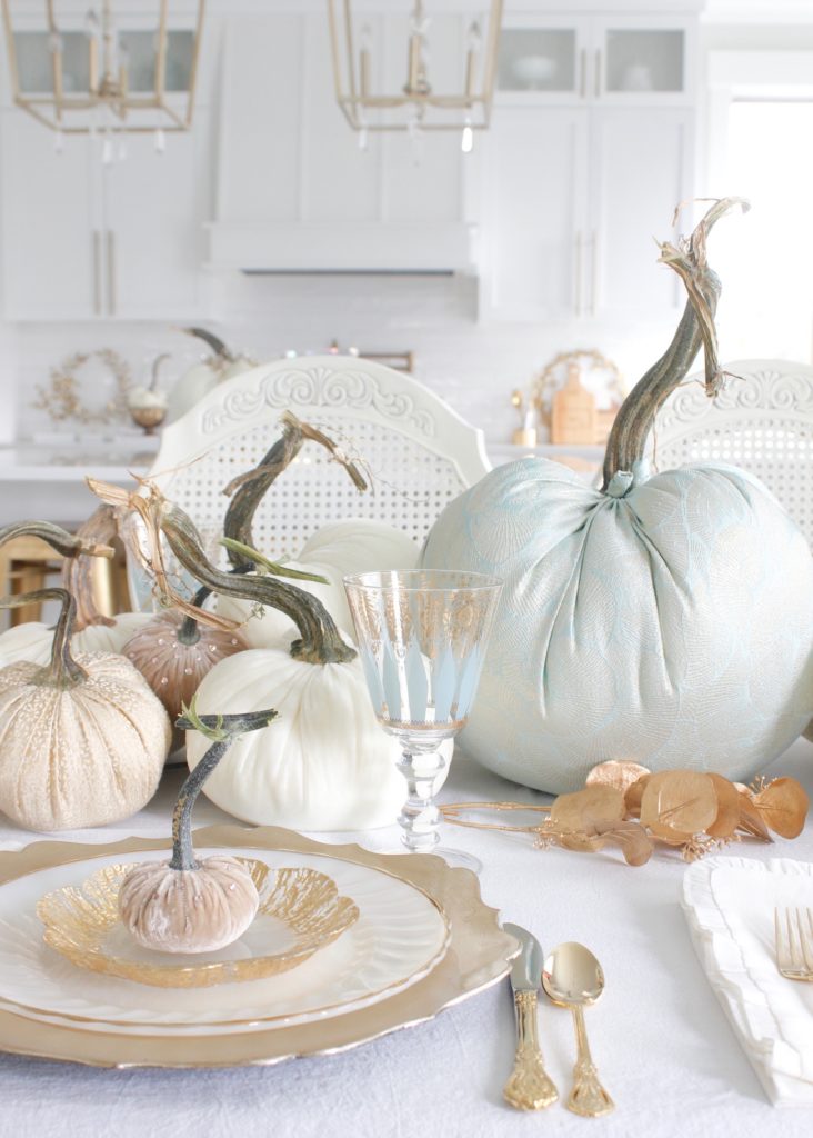 classy fall table, glam fall table, glam fall tablescape, elegant fall tablescape, white and gold fall table, gilded fall table, spa blue fall table, hot skwash velvet pumpkins, patina vie Aquarius goblets, ruffled tablecloth, ruffled ivory dinner napkins, gold flatware, gold-rimmed plates, gold flower butter plate dessert plates, vintage milk glass plates gold rim, gold chargers, pier1 gold eucalyptus stems, pier1 gold money glitter stems, white and gold fall kitchen decor, white velvet pumpkins, bellacor minka lavery pendants, white kitchen design, velvet pumpkins with Swarovski crystals, French country dining set, coastal kitchen, transitional kitchen, contemporary white elegant kitchen