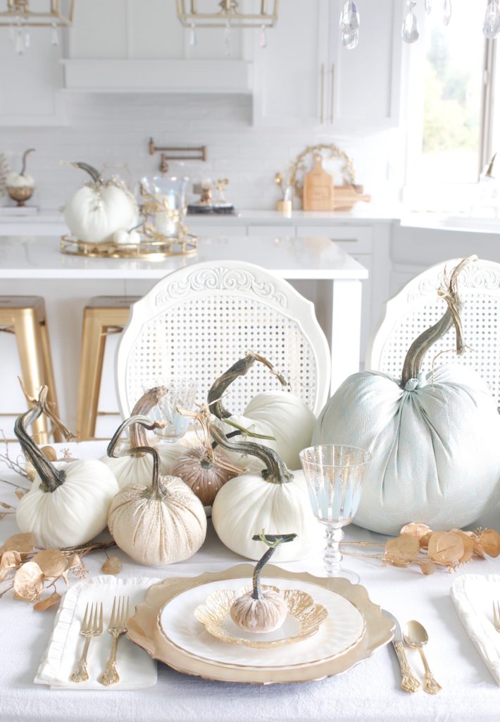 classy fall table, glam fall table, glam fall tablescape, elegant fall tablescape, white and gold fall table, gilded fall table, spa blue fall table, hot skwash velvet pumpkins, patina vie Aquarius goblets, ruffled tablecloth, ruffled ivory dinner napkins, gold flatware, gold-rimmed plates, gold flower butter plate dessert plates, vintage milk glass plates gold rim, gold chargers, pier1 gold eucalyptus stems, pier1 gold money glitter stems, white and gold fall kitchen decor, white velvet pumpkins, bellacor minka lavery pendants, white kitchen design, velvet pumpkins with Swarovski crystals, French country dining set, coastal kitchen, transitional kitchen, contemporary white elegant kitchen