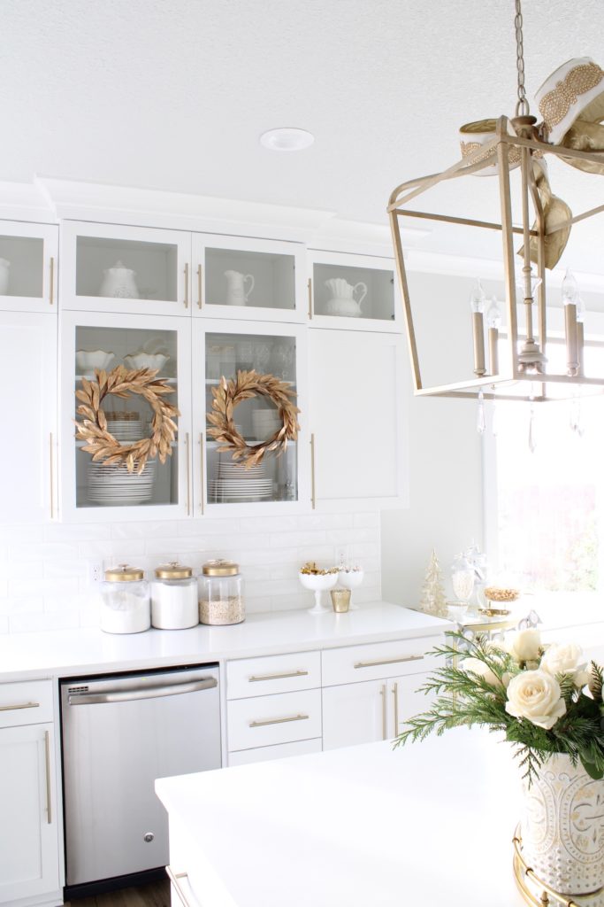 gold wreaths on white cabinets,white and gold Christmas kitchen, glam Christmas kitchen, ribbon bows on kitchen pendants lighting, Christmas bows on kitchen lights, elegant Christmas kitchen, classy Christmas kitchen decorating, d. Stevens white and gold rhinestone Christmas ribbon, specialty white velvet gold rhinestone wired edge ribbon, gold barstools, Christmas floral arrangements, white and gold Christmas wreath, white kitchen design, white Christmas decor, white and gold Christmas kitchen decor