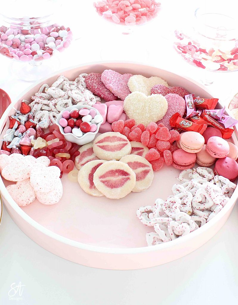 Valentine's Day dessert board, Valentine's Day charcuterie dessert board, dessert tray, dessert board, dessert candy board, dessert charcuterie board tray, pink circle round tray, pink candy dessert cookie tray, white kitchen entertaining, white kitchen island, white and gold decor, white and gold kitchen design, elegant glam white kitchen, white kitchen island, gold brass pendant kitchen lighting, Lindt chocolates, ghiradelli chocolates, Valentine's Day chocolate candies, dessert ideas, the prettiest dessert board ever, blogger dessert board, candy board tray, valentine's fashion, top knot pearl headband, voluspa candle, French pink Valentine's Day macarons, Reese's peanut butter hearts, Valentine's Day heart and lips cookies, Whole Foods market valentine's cookies