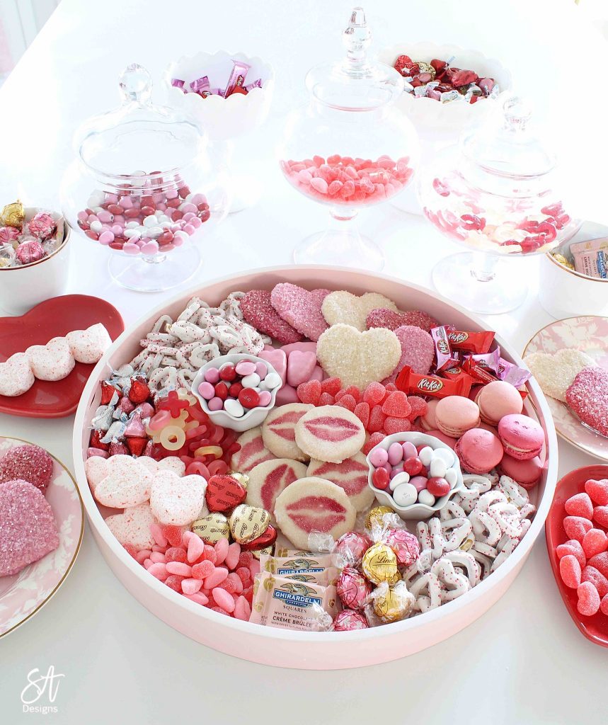 Valentine's Day dessert board, Valentine's Day charcuterie dessert board, dessert tray, dessert board, dessert candy board, dessert charcuterie board tray, pink circle round tray, pink candy dessert cookie tray, white kitchen entertaining, white kitchen island, white and gold decor, white and gold kitchen design, elegant glam white kitchen, white kitchen island, gold brass pendant kitchen lighting, Lindt chocolates, ghiradelli chocolates, Valentine's Day chocolate candies, dessert ideas, the prettiest dessert board ever, blogger dessert board, candy board tray, valentine's fashion, top knot pearl headband, voluspa candle, French pink Valentine's Day macarons, Reese's peanut butter hearts, Valentine's Day heart and lips cookies, Whole Foods market valentine's cookies