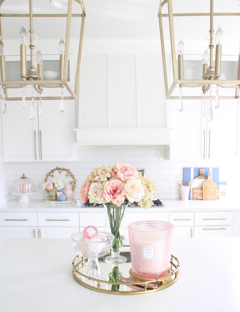 pink and blue spring kitchen decor, white kitchen design, white and gold kitchen, voluspa large 5 wick candle, voluspa macaron candles, white hood, white and gold kitchen, kitchen goals, Caitlin Wilson blue bread cutting board French blue, blogger kitchen inspiration