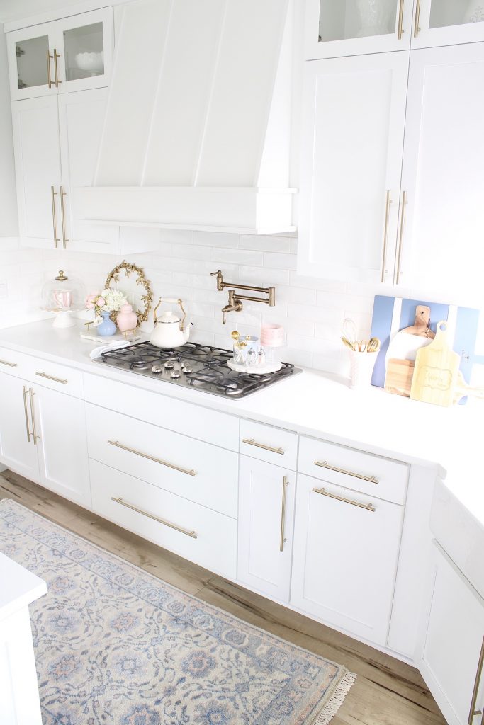 pink and blue spring kitchen decor, white kitchen design, white and gold kitchen, voluspa large 5 wick candle, voluspa macaron candles, white hood, white and gold kitchen, kitchen goals, Caitlin Wilson blue bread cutting board French blue, blogger kitchen inspiration