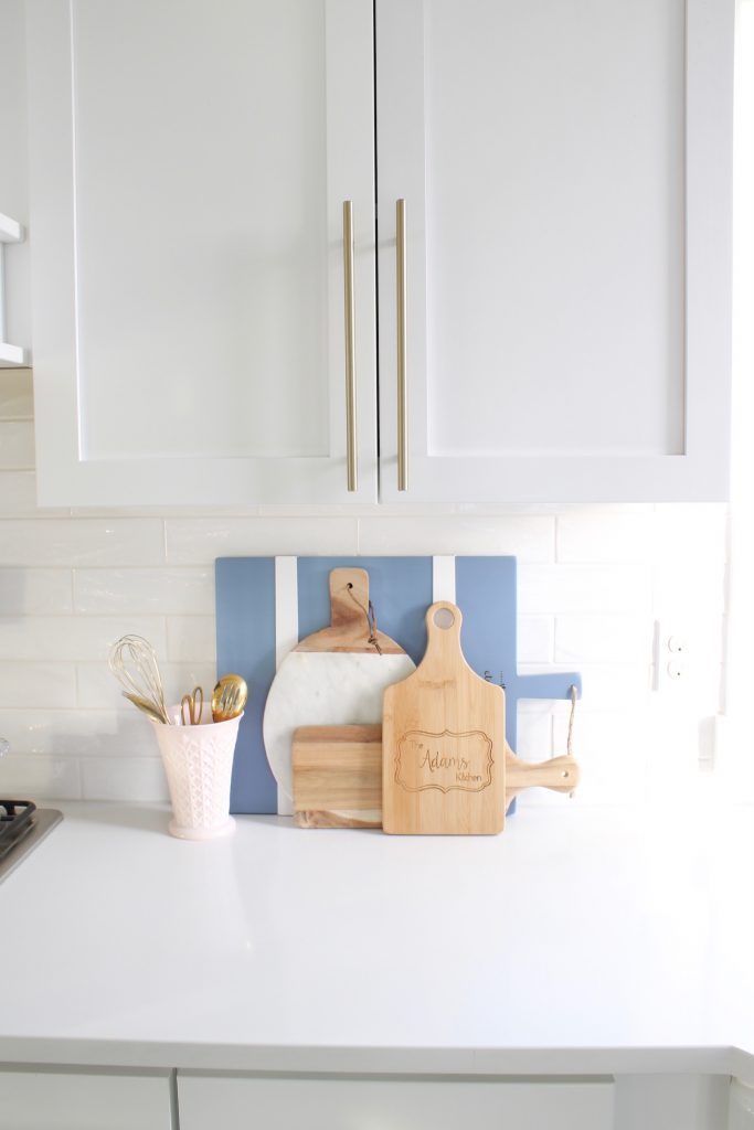 pink and blue spring kitchen decor, white kitchen design, white and gold kitchen, voluspa large 5 wick candle, voluspa macaron candles, white hood, white and gold kitchen, kitchen goals, Caitlin Wilson blue bread cutting board French blue, blogger kitchen inspiration