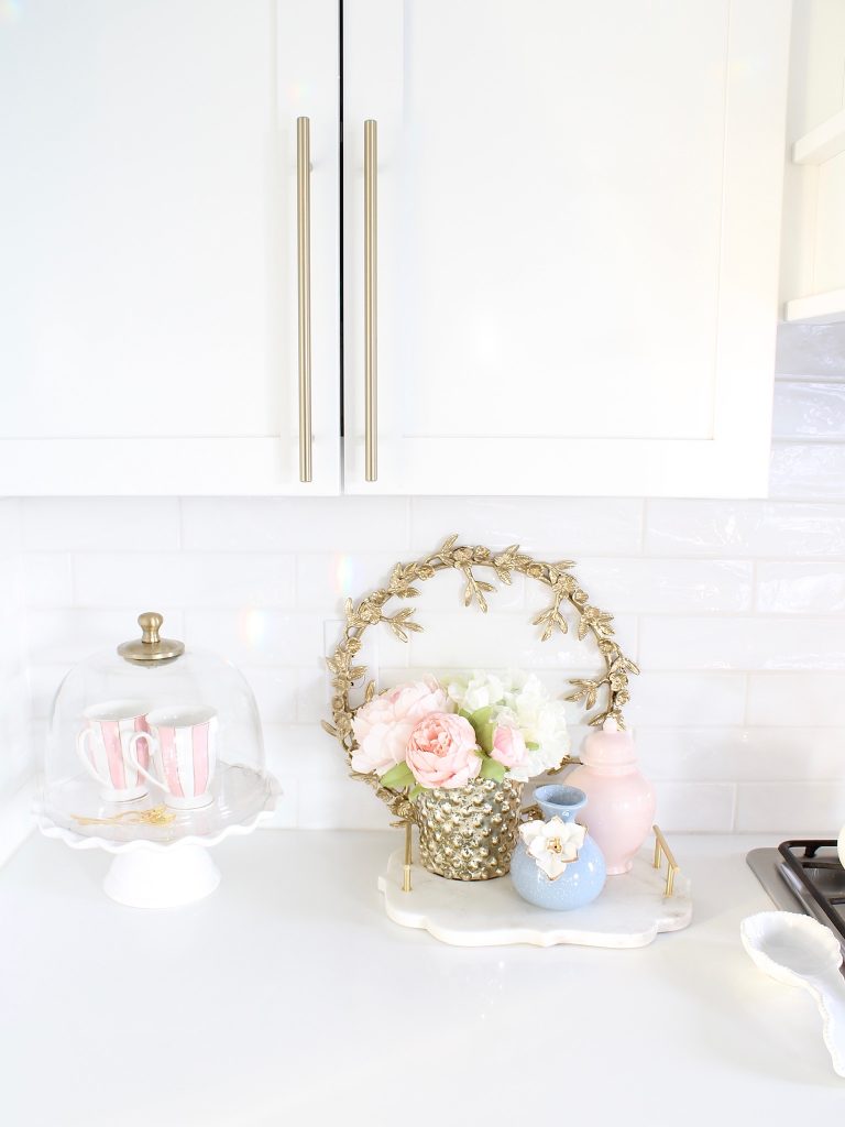 pink and blue spring kitchen decor, white kitchen design, white and gold kitchen, voluspa large 5 wick candle, voluspa macaron candles, white hood, white and gold kitchen, kitchen goals, Caitlin Wilson blue bread cutting board French blue, blogger kitchen inspiration