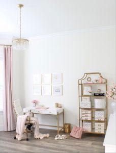 white and gold office, blush office, glam office, etagere gold shelves, Maltese dog, nesting boxes, home office, feminine office, diptyque candles used a flower vase, upcycled diptyque candle holder, white ginger jar pink cherry blossom stems, white matted gold frame set, office accessories, desk accessories, leopard slippers, white and gold leather office chair with wheels, pink pom pom throw blanket, blush tassel tote, gold office shelves, office shelving, how to decorate shelves, blogger office