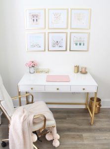 white and gold office, blush office, glam office, etagere gold shelves, Maltese dog, nesting boxes, home office, feminine office, diptyque candles used a flower vase, upcycled diptyque candle holder, white ginger jar pink cherry blossom stems, white matted gold frame set, office accessories, desk accessories, leopard slippers, white and gold leather office chair with wheels, pink pom pom throw blanket, blush tassel tote, gold office shelves, office shelving, how to decorate shelves, blogger office