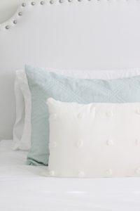 gold sunburst wall mirror, large gold lamps, serene spa blue guest bedroom, walmart home, white nightstands, white modern headboard, spa blue quilt bedding, white pom pom bed oblong pillows