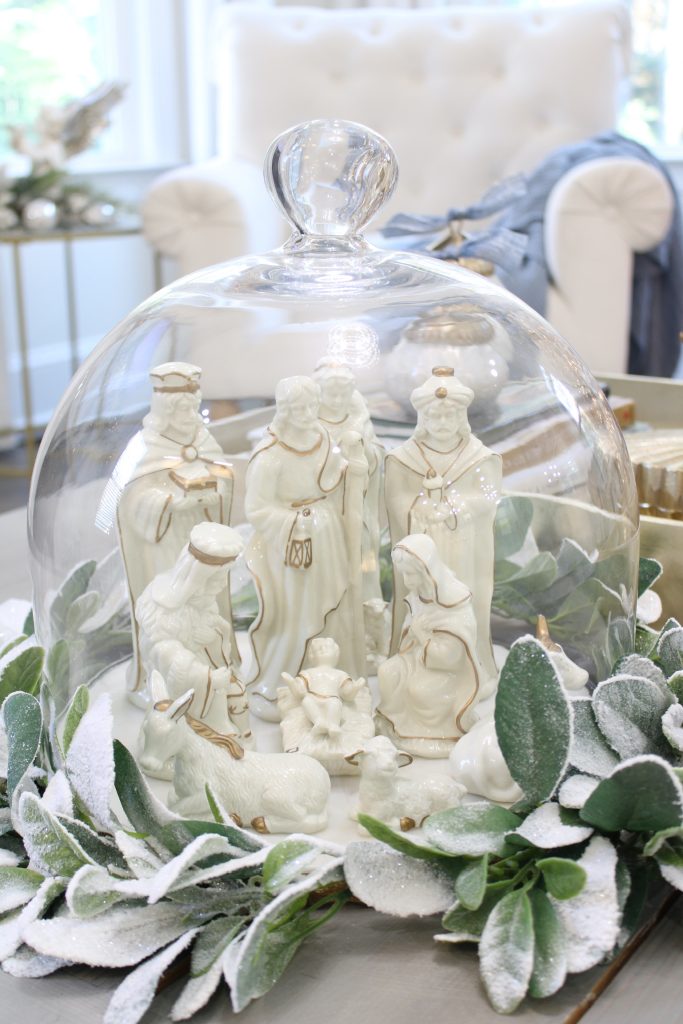 white and gold christmas nativity set under glass cloche